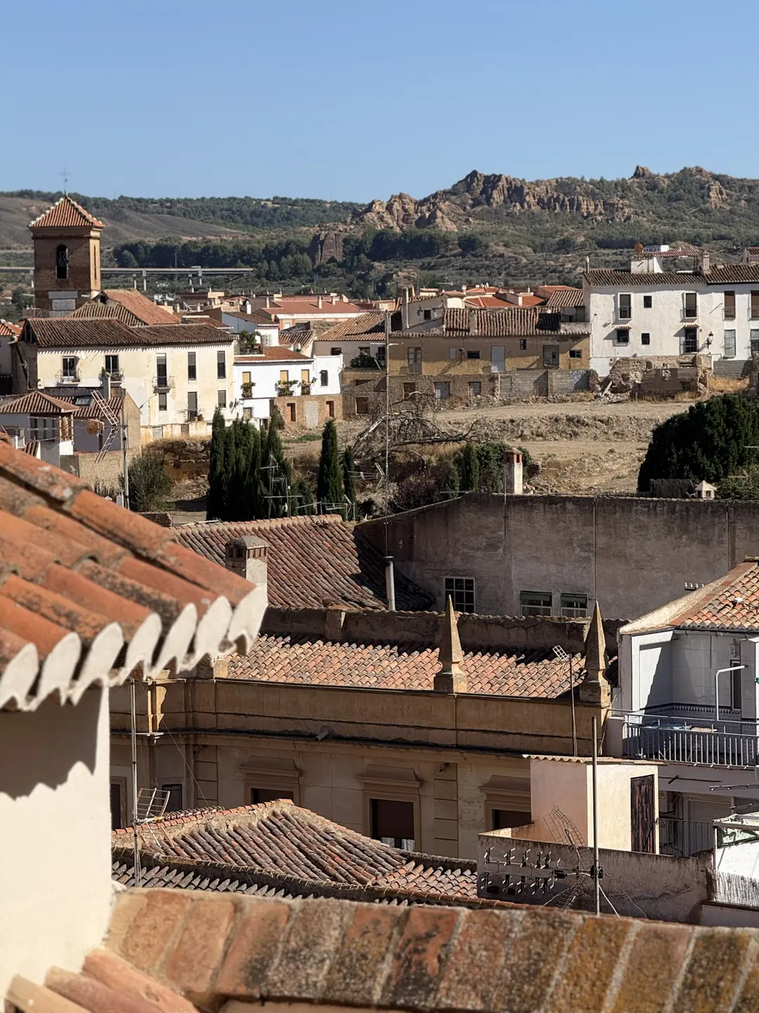 Tiled rooftops of an Andalusian old town with eroded badland hills behind, on the Ride Trans Nevada route