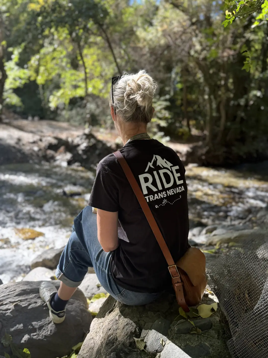 Ride Trans Nevada team member relaxing beside a mountain river